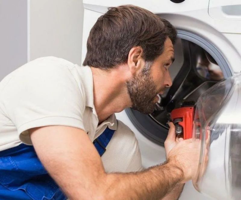 Мастер ремонтирует бак стиральной машины